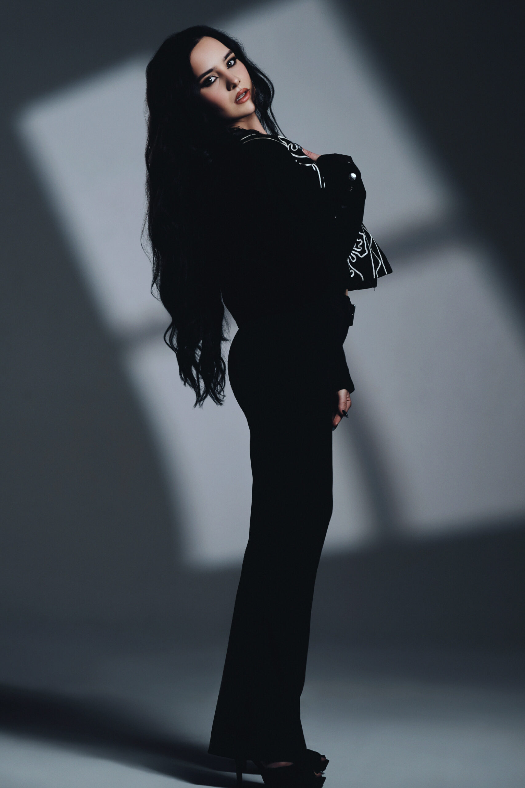 Full-body promotional portrait of artist Chigri posing in black attire against a shadowed, minimalistic background.
