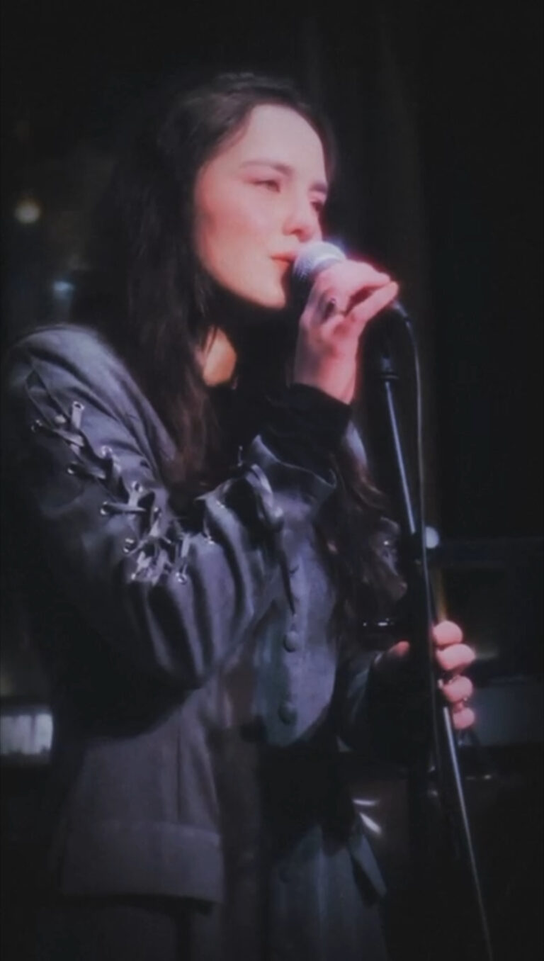 Chigri performing live on stage in an atmospheric, minimalistic setting.